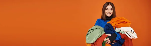 Banner of joyful woman with brunette hair holding colorful autumnal clothes,  black friday concept — Stock Photo