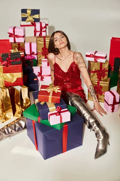 Stylish woman in festive dress and shoes sitting on floor among presents, holiday gifts concept — Stock Photo