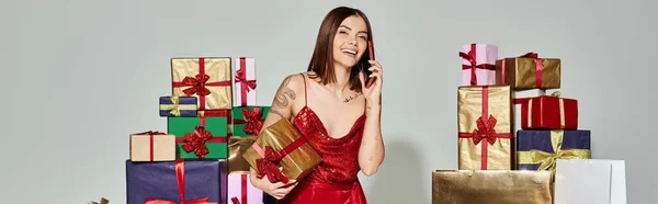 Cheerful woman surrounded by presents talking actively on phone, holiday gifts concept, banner — Stock Photo