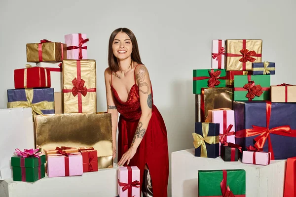 Glückliche junge Frau umgeben von Geschenken, die fröhlich in die Kamera lächeln, Konzept für Weihnachtsgeschenke — Stockfoto