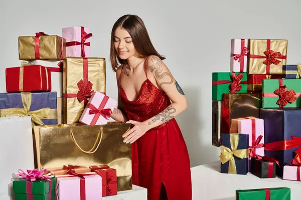 Smiley glückliche Dame im roten Kleid verpackt Geschenk in Tasche und lächelt fröhlich, Weihnachtsgeschenke Konzept — Stockfoto