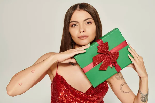 Beautiful woman with piercing and tattoos with present in hands looking at camera, holiday gifts — Stock Photo