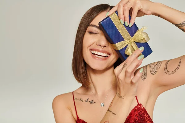 Attractive lady smiling sincerely with closed eyes with present in front of her face, holiday gifts — Stock Photo