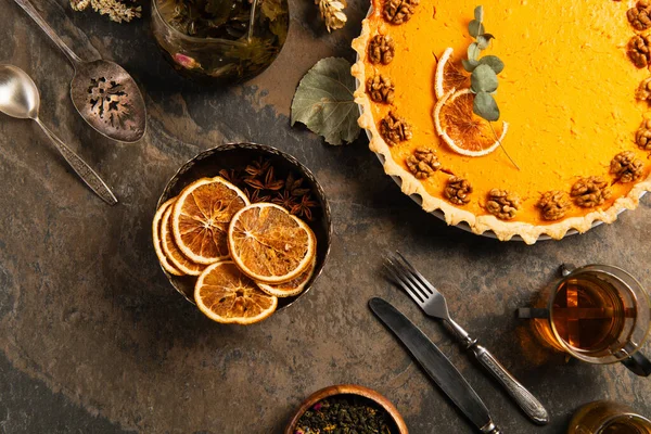 День благодарения на фоне вкусного тыквенного пирога, винтажных столовых приборов и апельсиновых ломтиков на каменном столе — стоковое фото