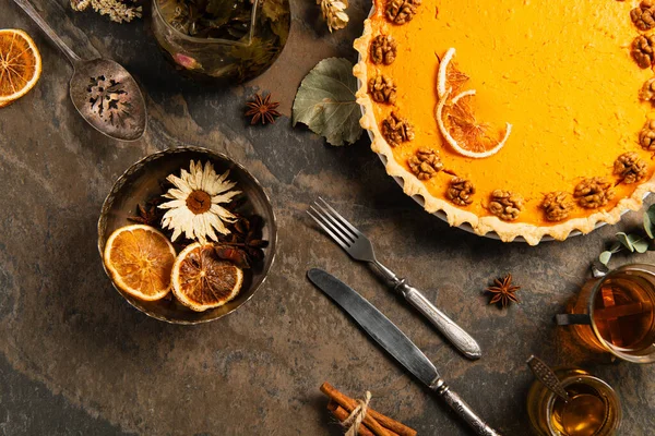 Тыквенный пирог украшен грецкими орехами и апельсиновыми ломтиками рядом с травами и специями, благодарственная композиция — стоковое фото