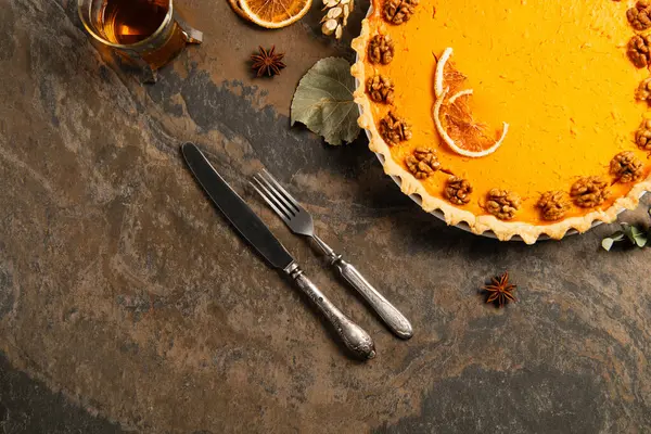 Тыквенный пирог с грецкими орехами и апельсиновыми ломтиками рядом со старинными столовыми приборами и теплым чаем, в обстановке Дня благодарения — стоковое фото