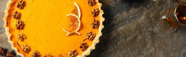Delicious thanksgiving symbol, pumpkin pie with walnuts and orange slices on stone backdrop, banner — Stock Photo