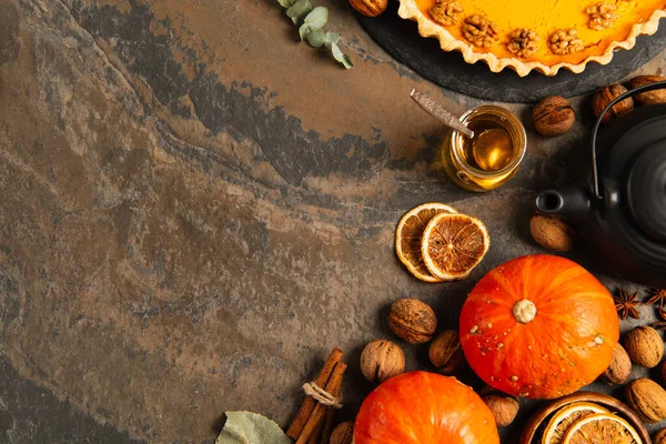 Thanksgiving composition, ripe pumpkins near walnuts, honey and delicious pumpkin pie on stone table — Stock Photo