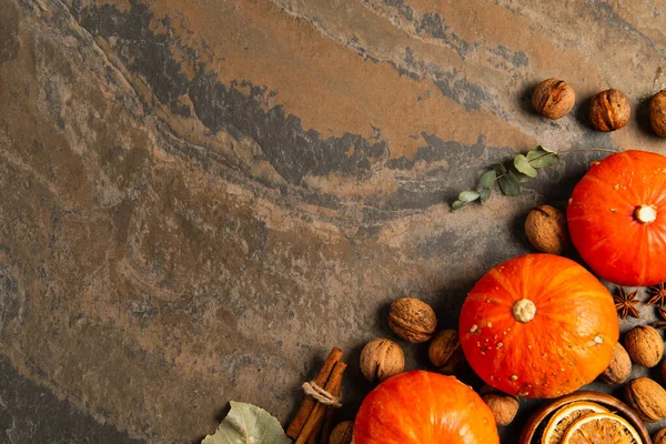 Zucche arancioni mature vicino alle noci e bastoncini di cannella su sfondo di pietra testurizzata, Ringraziamento — Foto stock