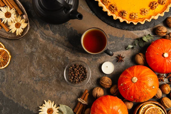 Thanksgiving toile de fond avec des citrouilles mûres, tarte aux citrouilles délicieuse et thé aromatique sur la surface de la pierre — Photo de stock