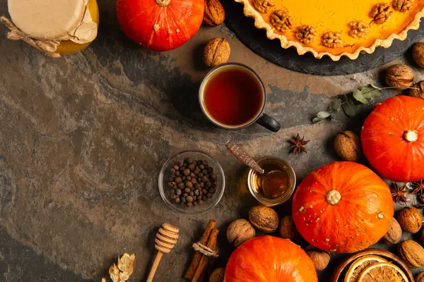 Thanksgiving still life, pumpkin pie near ripe gourds, tea with honey and spices on stone backdrop — Stock Photo