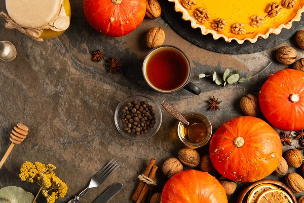 Colorful thanksgiving setting with ripe gourds and pumpkin pie near tea, honey and seasonal objects — Stock Photo