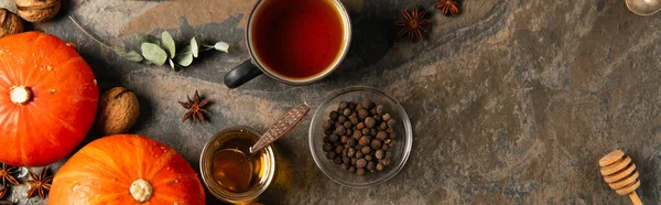 Апельсиновые тыквы возле теплого чая и ароматного меда из каменного стола, концепция благодарения, баннер — стоковое фото