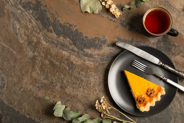 Seasonal thanksgiving setting, black plate with pumpkin pie near herbs and warm tea on stone table — Stock Photo