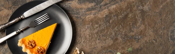 Assiette en céramique noire avec tarte à la citrouille thanksgiving et couverts vintage sur table en pierre, bannière — Photo de stock