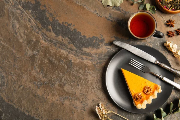 Erntedank-Konzept, Kürbiskuchen und Besteck in der Nähe von warmem Tee und aromatischen Kräutern auf Steinoberfläche — Stockfoto