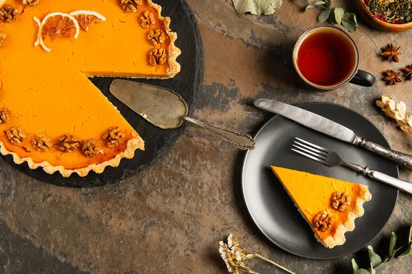 Thanksgiving pumpkin pie with walnuts and orange slices near vintage cutlery on rustic stone table — Stock Photo