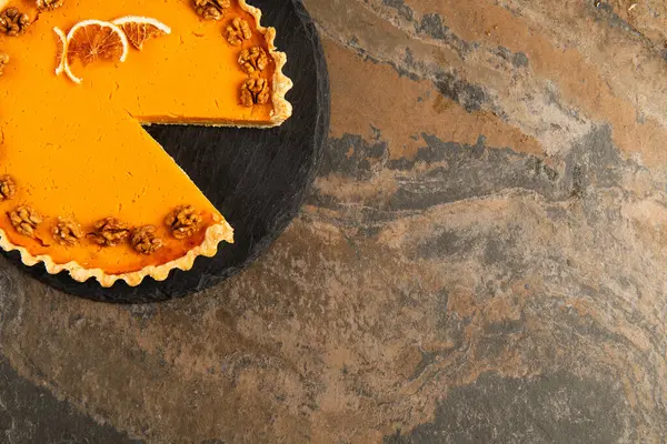 Pastel de acción de gracias brillante con nueces y rebanadas de naranja seca en la mesa de pizarra negra y la superficie de piedra - foto de stock