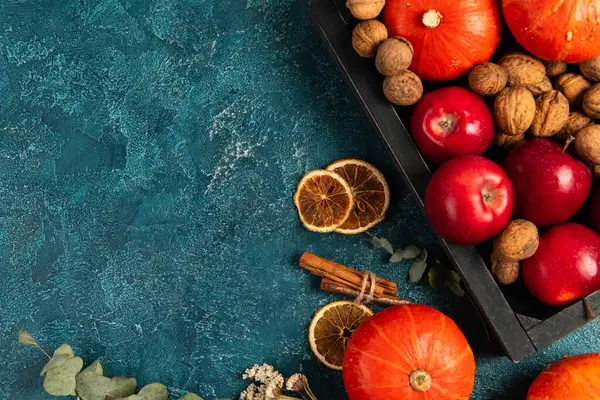 Pano de fundo de ação de graças, bandeja com colheita de outono perto de fatias de laranja e ervas na superfície texturizada azul — Fotografia de Stock