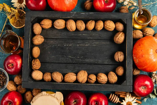 Colorido telón de fondo de acción de gracias con nueces en bandeja de madera negra rodeada de objetos de cosecha de otoño - foto de stock