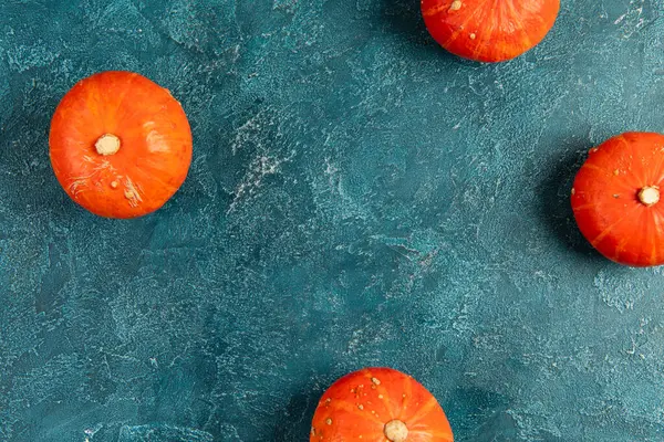 Sfondo del Ringraziamento, zucche arancione brillante su blu strutturato tavolo, prospettiva dall'alto verso il basso — Foto stock