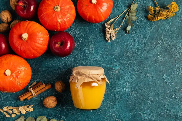 Telón de fondo de acción de gracias, calabazas cerca de tarro de miel y objetos de cosecha de otoño en la superficie de textura azul - foto de stock
