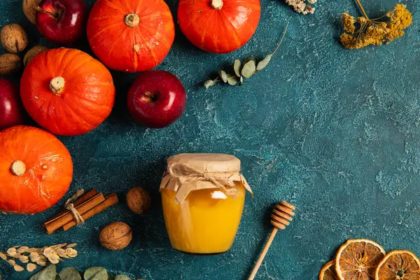 Tema de acción de gracias, calabazas cerca de tarro de miel y objetos de cosecha de otoño en la superficie de textura azul - foto de stock
