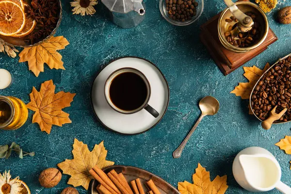Naturaleza muerta de acción de gracias, taza de café en la mesa de textura azul con hojas de arce y decoración otoñal - foto de stock