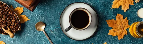 Xícara de café preto perto de folhas de bordo douradas na mesa texturizada azul, conceito de ação de graças, banner — Fotografia de Stock