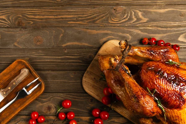 Cuisine thanksgiving toile de fond, dinde grillée près de couverts et tomates cerises rouges sur table en bois — Photo de stock