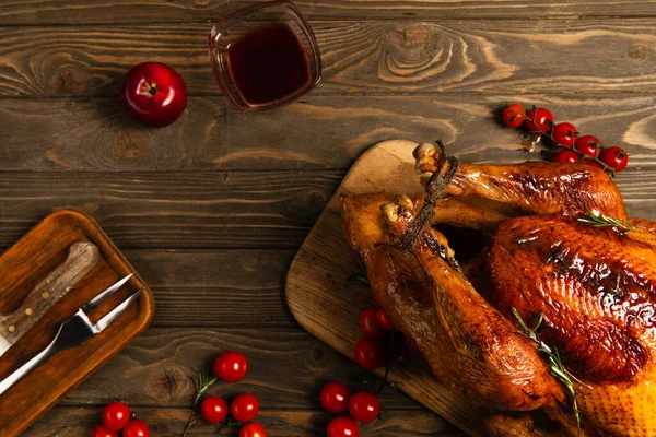 Thanksgiving turkey near red cherry tomatoes, apple and maple syrup on rustic wooden tabletop — Stock Photo