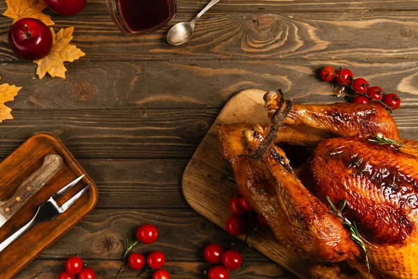 Thanksgiving still life, grilled turkey near maple syrup and cherry tomatoes on rustic wooden table — Stock Photo
