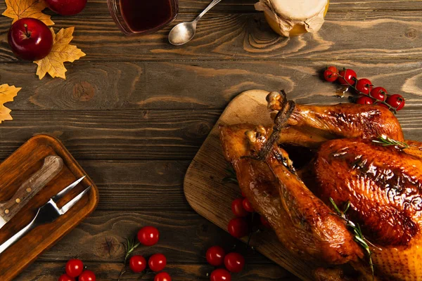 Roasted turkey near honey and maple syrup on wooden table with autumnal decor, thanksgiving — Stock Photo