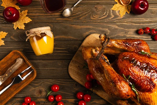Thanksgiving setting, grilled turkey near honey and cherry tomatoes on decorated wooden table — Stock Photo
