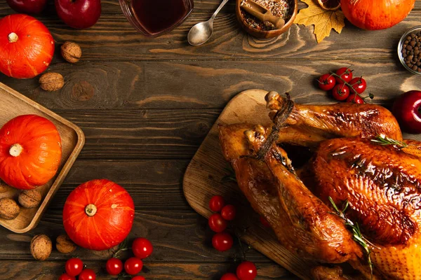 Thanksgiving dinner, roasted turkey near pumpkins and spices on wooden table with autumnal decor — Stock Photo