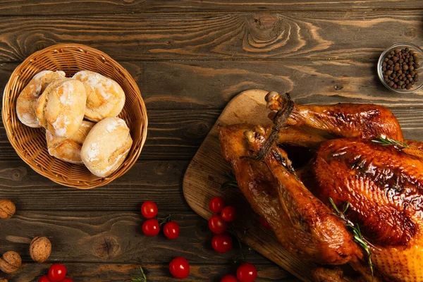 Thanksgiving toile de fond, dinde grillée avec des petits pains fraîchement cuits près de tomates cerises sur table en bois — Photo de stock