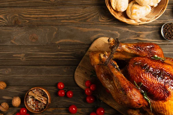 Erntedank-Dinner, frisch gebackenes Brot und rote Kirschtomaten neben gebratenem Truthahn auf Holztisch — Stockfoto