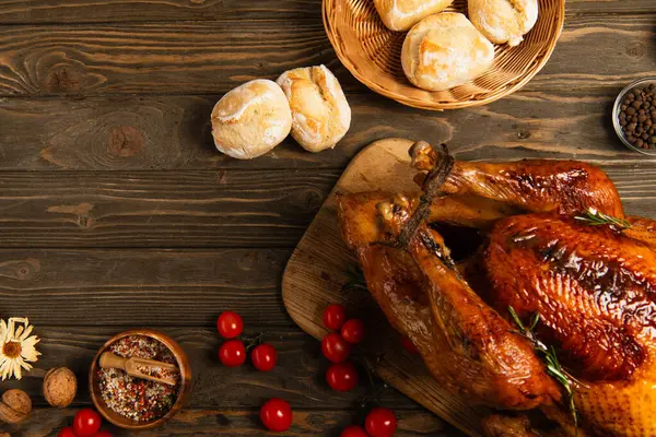 Wooden table with grilled turkey and buns near spices and cherry tomatoes, delicious thanksgiving — Stock Photo