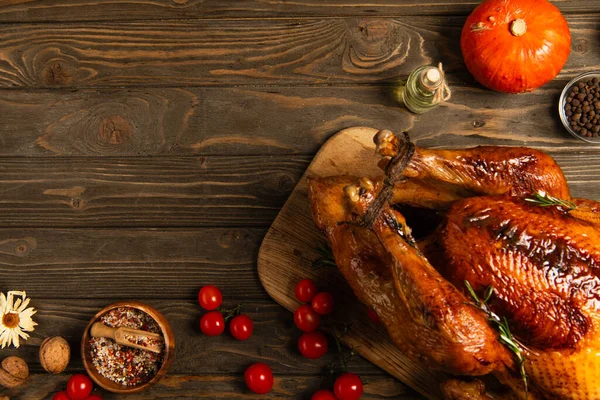 Grilled turkey and freshly baked buns near spices and cherry tomatoes on wooden table, thanksgiving — Stock Photo