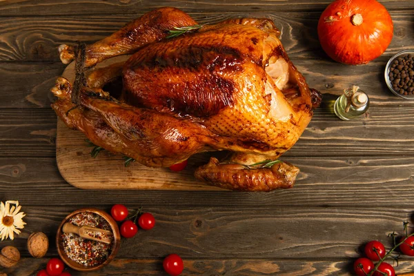 Traditional thanksgiving dinner, roasted turkey near cherry tomatoes and pumpkin on wooden table — Stock Photo