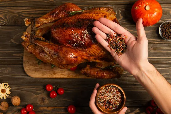 Cropped view of man with wooden bowl and spices near thanksgiving turkey, festive dinner preparation — Stock Photo