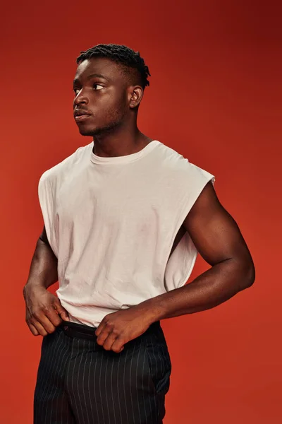 Hot african american guy in white tank top standing and looking away on red, urban fashion — Stock Photo