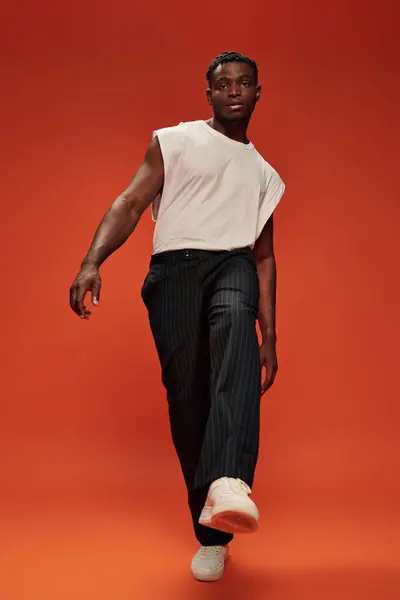 Full length of charismatic and fashionable african american man posing with outstretched leg on red — Stock Photo