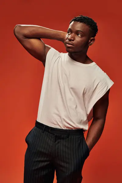 Junger afrikanisch-amerikanischer Mann in trendiger Freizeitkleidung hält die Hand in der Tasche und schaut weg auf rot — Stockfoto