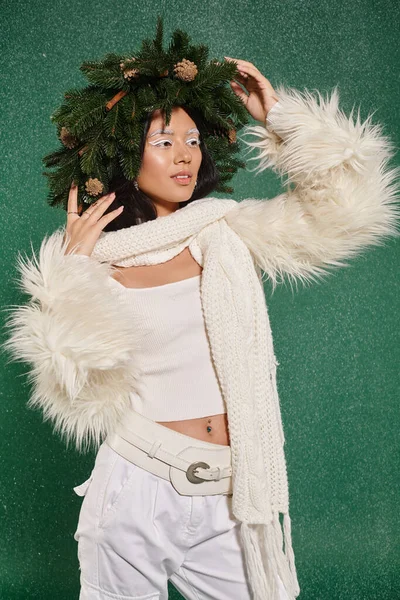 Mode d'hiver, jolie femme avec couronne naturelle posant dans des vêtements élégants blancs sous la neige tombante — Photo de stock