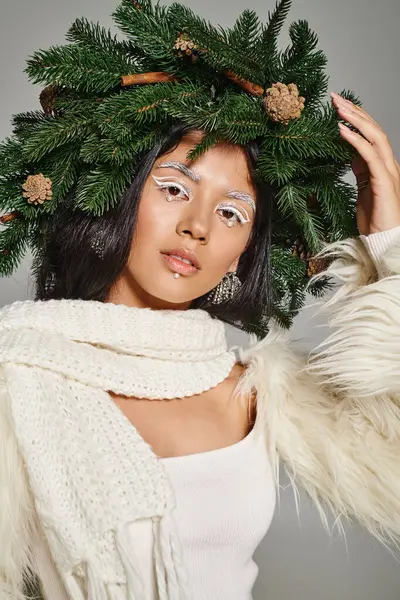 Attraktive Winterkönigin mit weißen Augen Make-up und Perlen im Gesicht posiert in Kranz auf grauem Hintergrund — Stockfoto