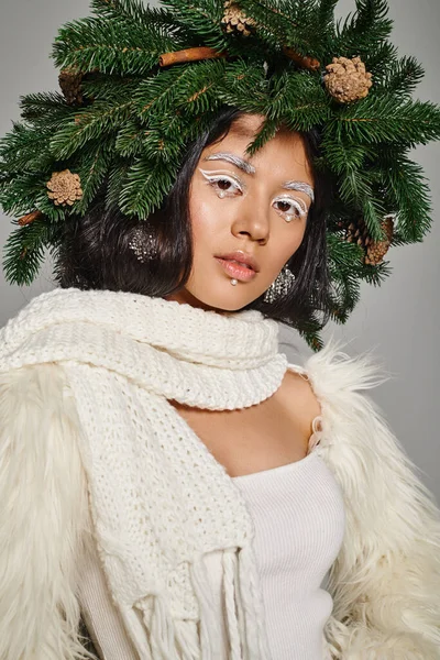 Schöne Winterkönigin mit weißen Augen Make-up und Perlen im Gesicht posiert in Kranz auf grauem Hintergrund — Stockfoto