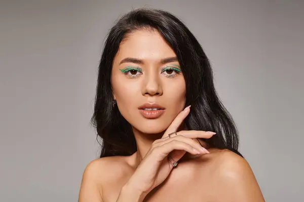 Beautiful asian woman with green eyeliner and bare shoulders posing on grey background, bold makeup — Stock Photo