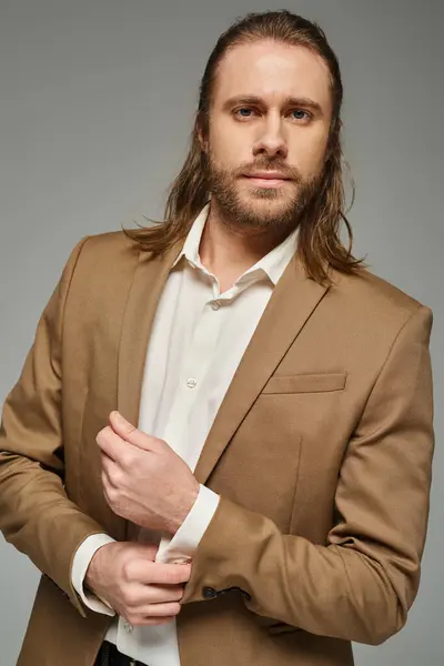 Bonito empresário com barba e cabelos longos posando em blazer no fundo cinza, traje formal — Fotografia de Stock