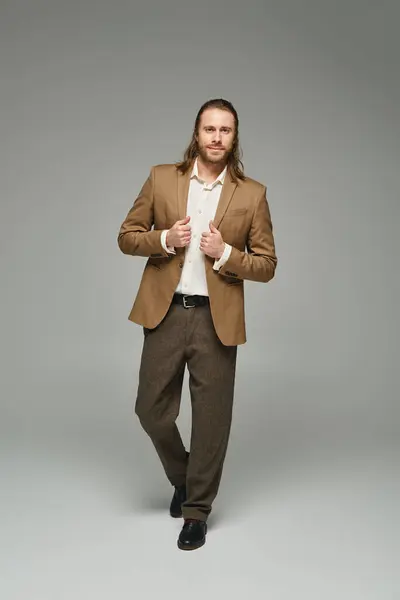 Full length of businessman with beard and long hair posing on grey backdrop, formal attire — Stock Photo